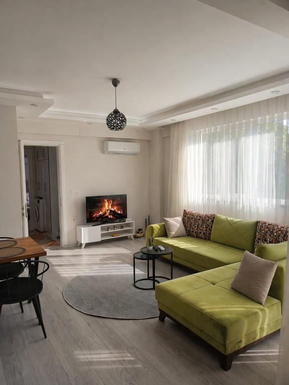 a living room with a green couch and a fireplace at YoYo Apart in Dalaman