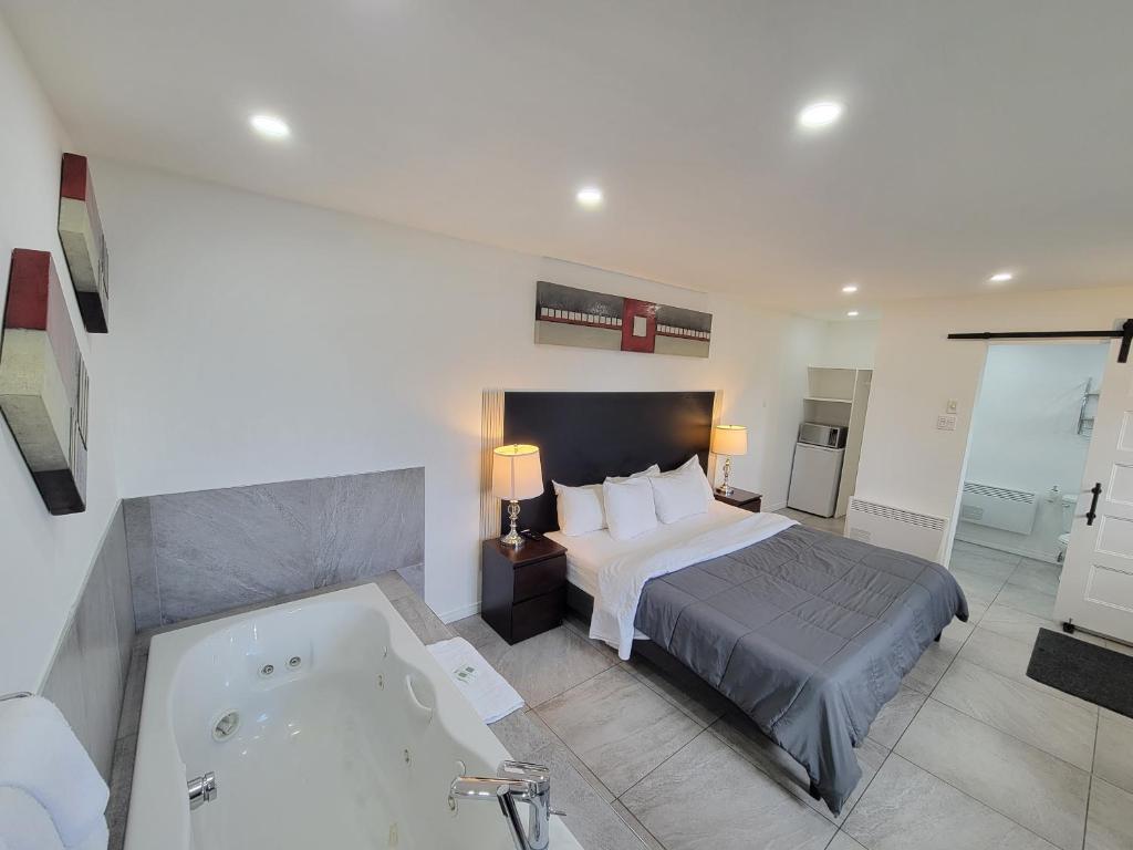 a bedroom with a bed and a bath tub at Motel Grande Ile in Salaberry-de-Valleyfield