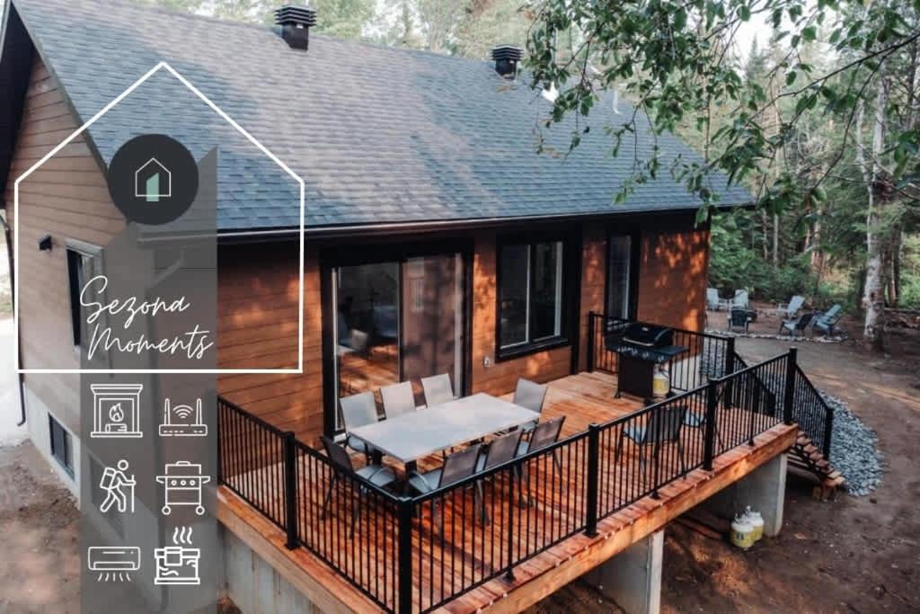 a house with a large deck with a patio at Nature & lake access Tremblant in Saint-Rémi-dʼAmherst