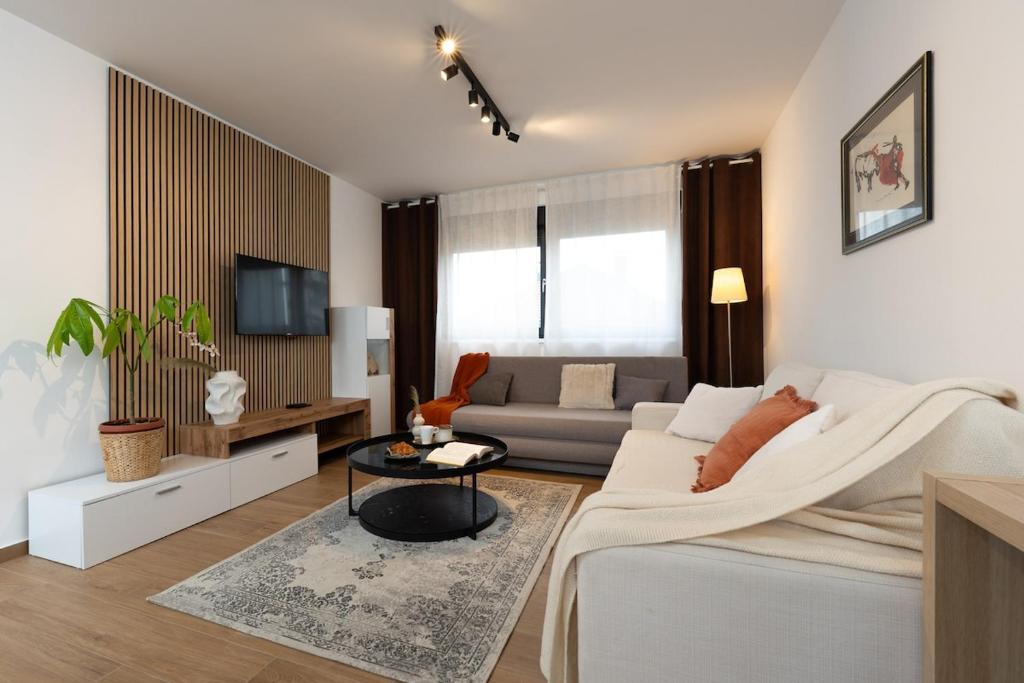 a white living room with a couch and a tv at Secret Garden Apartman in Varaždin