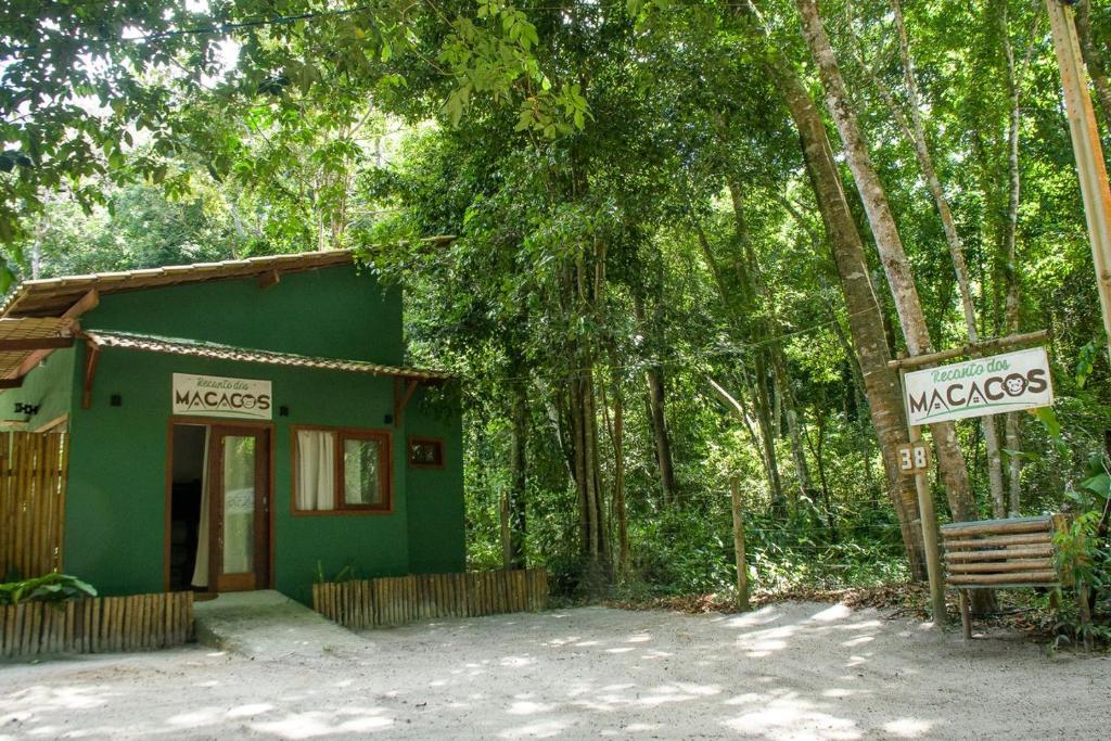 a small green building in the middle of a forest at Chale 4 com Churrasqueira e Ar a 200m da Praia in Prado