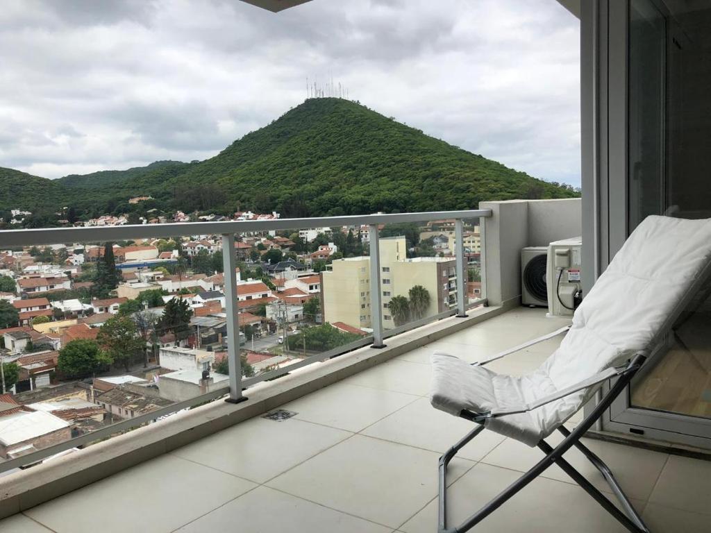 a chair on a balcony with a view of a city at Depto Altos Juramento in Salta