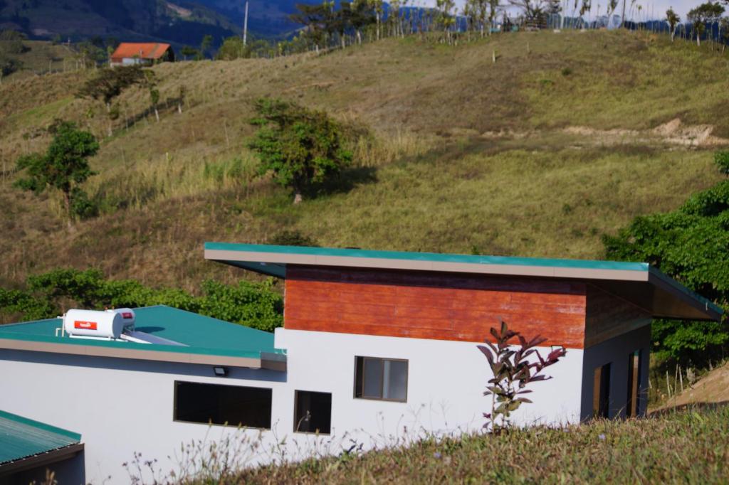 a house with a green roof on a hill at Finca Las Raíces Posada Rural in Zarcero