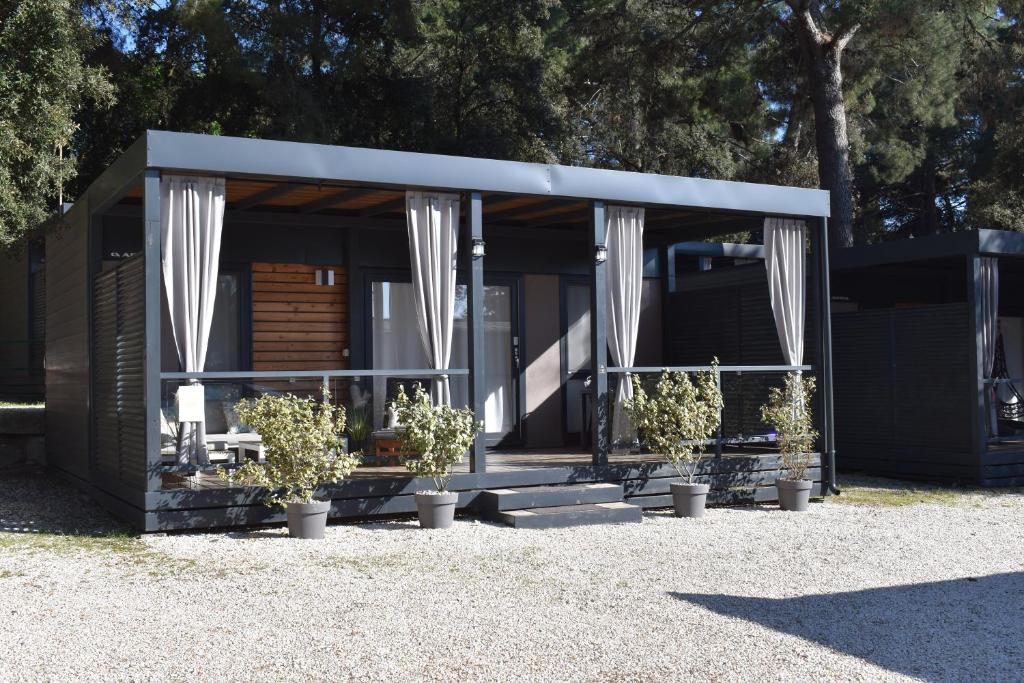 a small building with white curtains and potted plants at Perla - Lux Mobile Homes in Rovinj