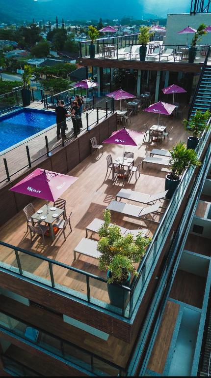 a balcony with tables and purple umbrellas on a building at MK Flat - A 2 quadras do mar in Matinhos