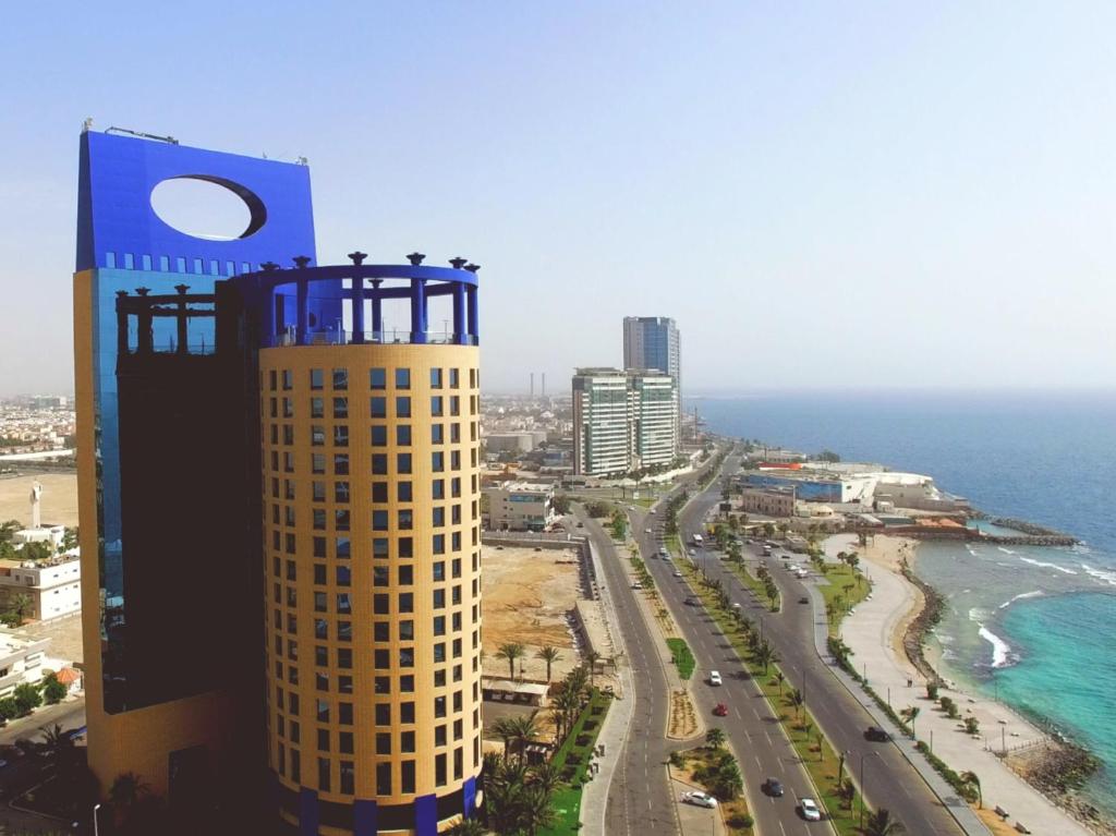 wysoki budynek obok plaży i oceanu w obiekcie Rosewood Jeddah w mieście Dżudda