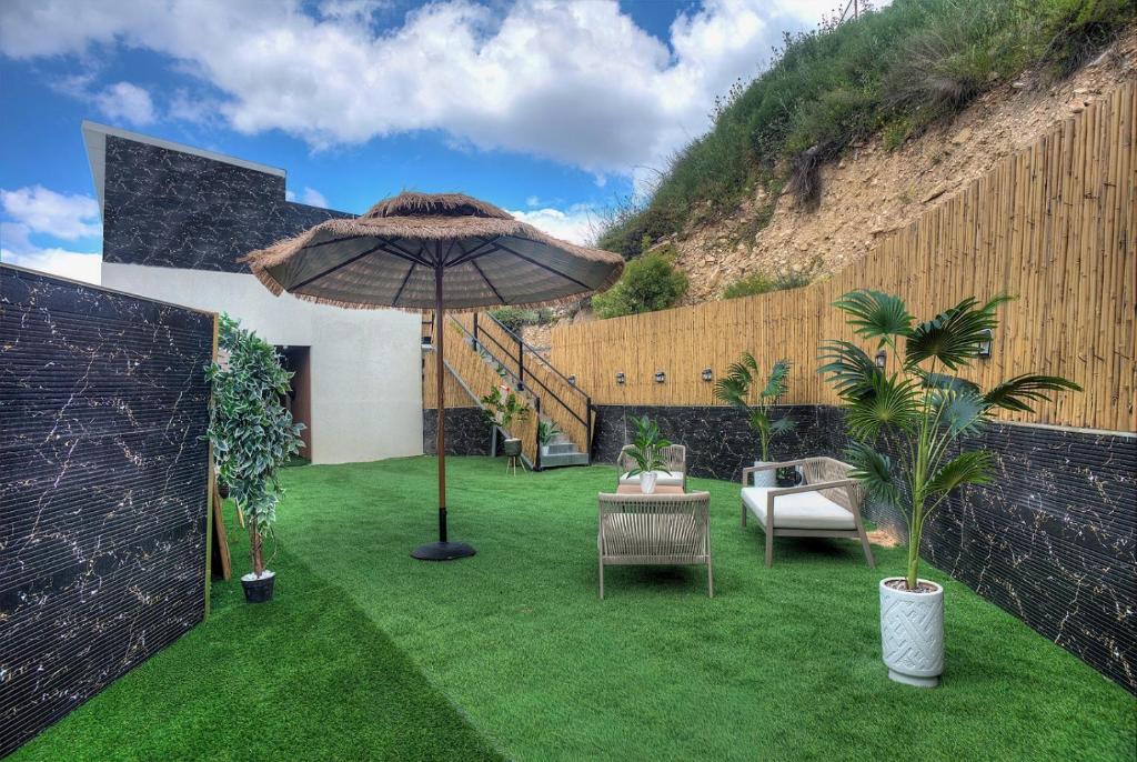 a patio with an umbrella and chairs on grass at אחוזת בין ההרים צפת in Safed