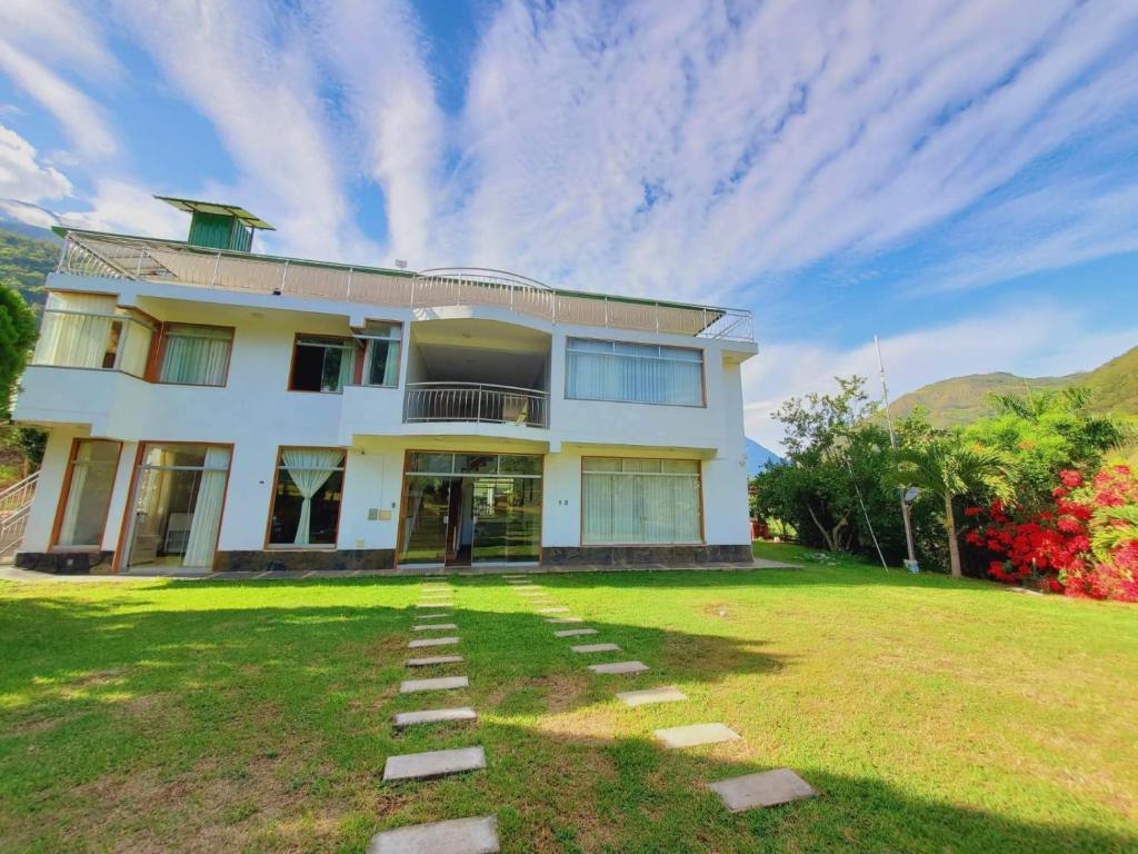 a large white house with a grass yard at Hotel Paraíso in San Antonio