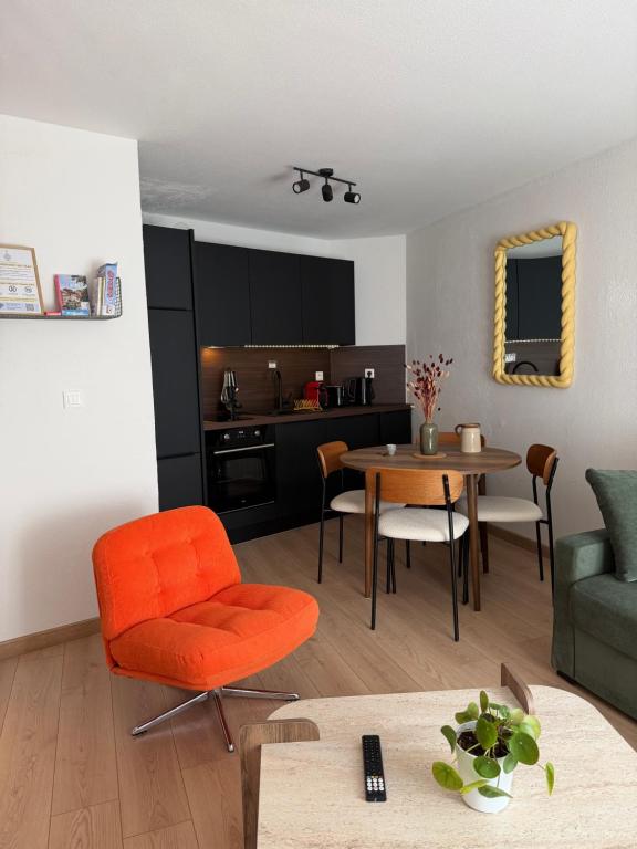 a living room with an orange chair and a table at Le charmant Duplex de la Bibliothèque - Vélos Friendly- Centre historique et proche Europa-Park in Sélestat