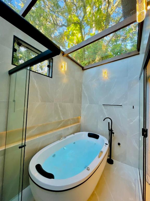 a bathroom with a large tub in a room with windows at Estalagem Cachoeira do Pimenta in Cunha