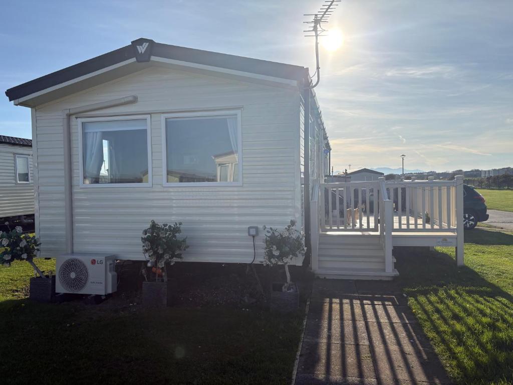 a small white tiny house with a porch at Shivvys at sandylands in Stevenston