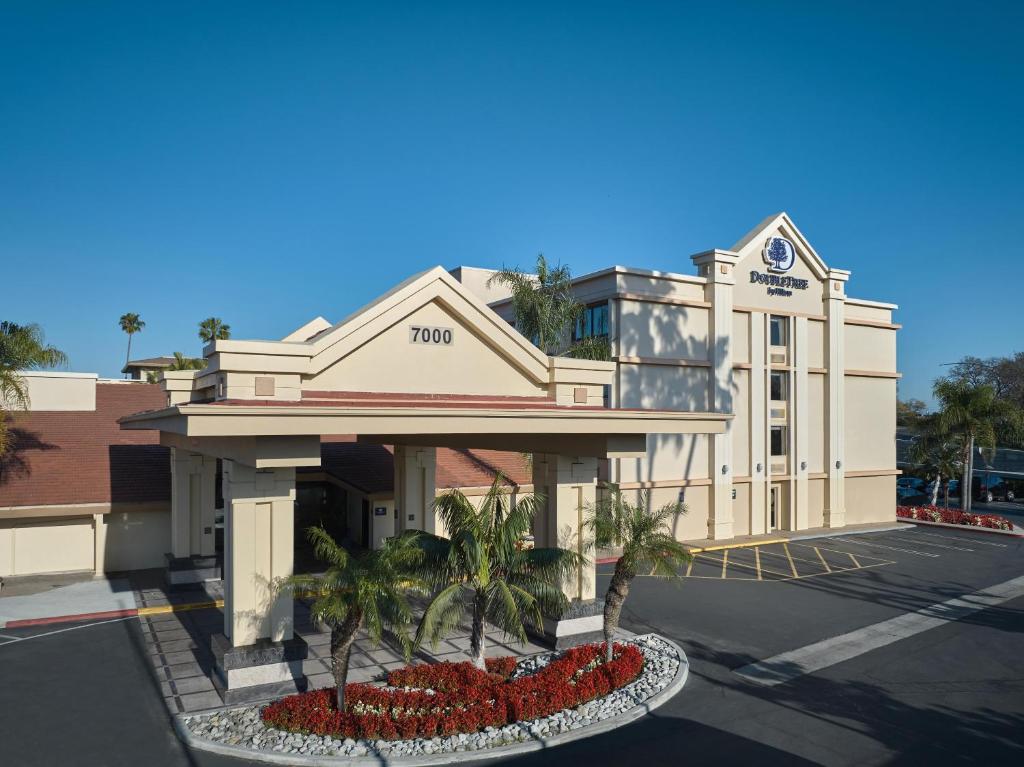 a building with palm trees in front of a parking lot at Doubletree by Hilton Buena Park in Buena Park