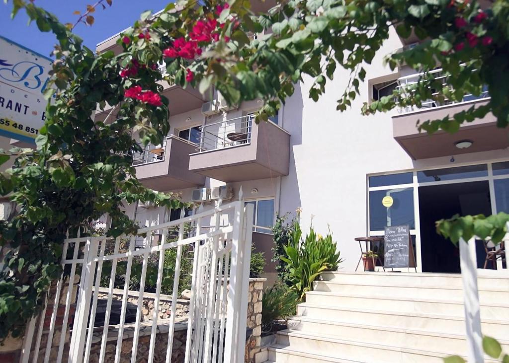 ein weißes Gebäude mit einem weißen Tor und Blumen in der Unterkunft Mare Blue Hotel Drymades in Dhërmi