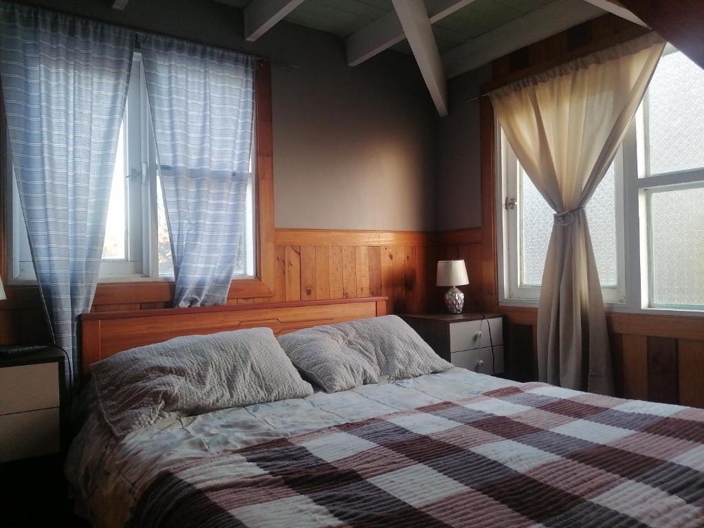 a bedroom with a bed and two windows at Habitación tu Refugio in Isla Negra