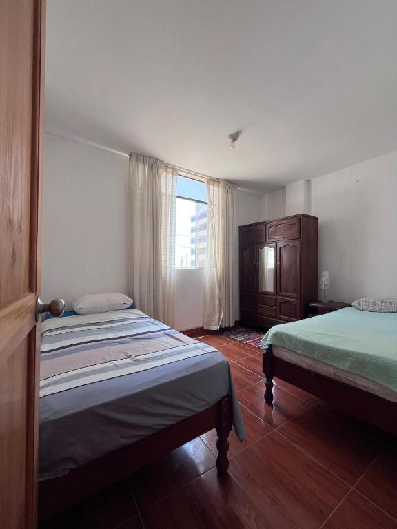 a bedroom with two beds and a window at Minidpto Wayra Huanchaco in Huanchaco