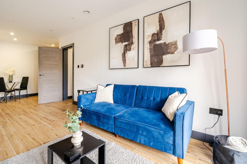 a blue couch in a living room with a table at Luxury Apartment Close to Elstree & Borehamwood Station in Borehamwood