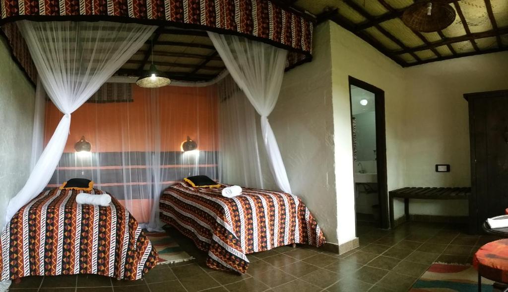 2 Betten in einem Zimmer mit Vorhängen in der Unterkunft Osoita Lodge in Nairobi