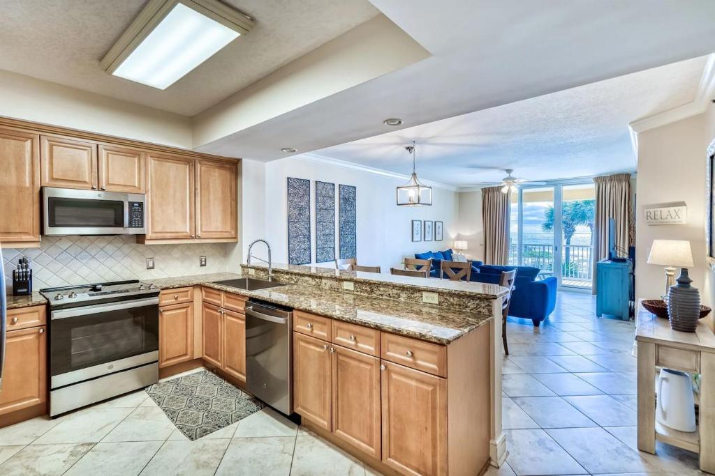a kitchen with wooden cabinets and a living room at 3BR Beachfront Huge Balcony 2 Pools Luxury in Fort Walton Beach