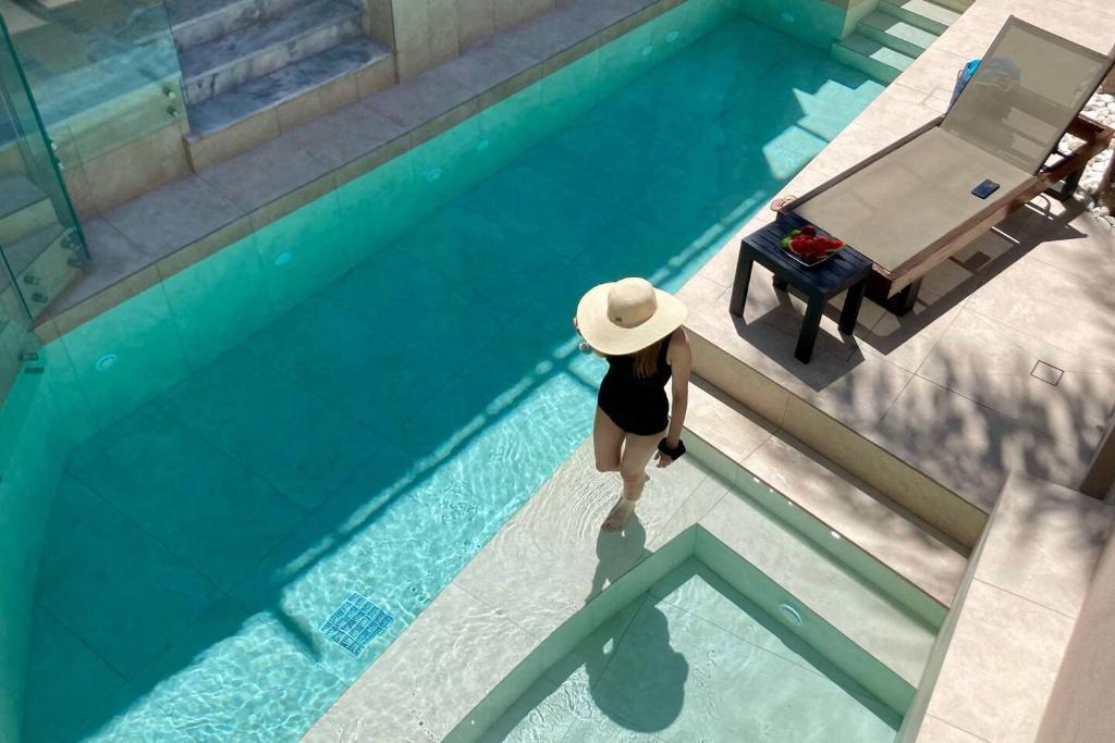 a woman in a hat standing next to a swimming pool at Villa Kallergi Athena in Loutra
