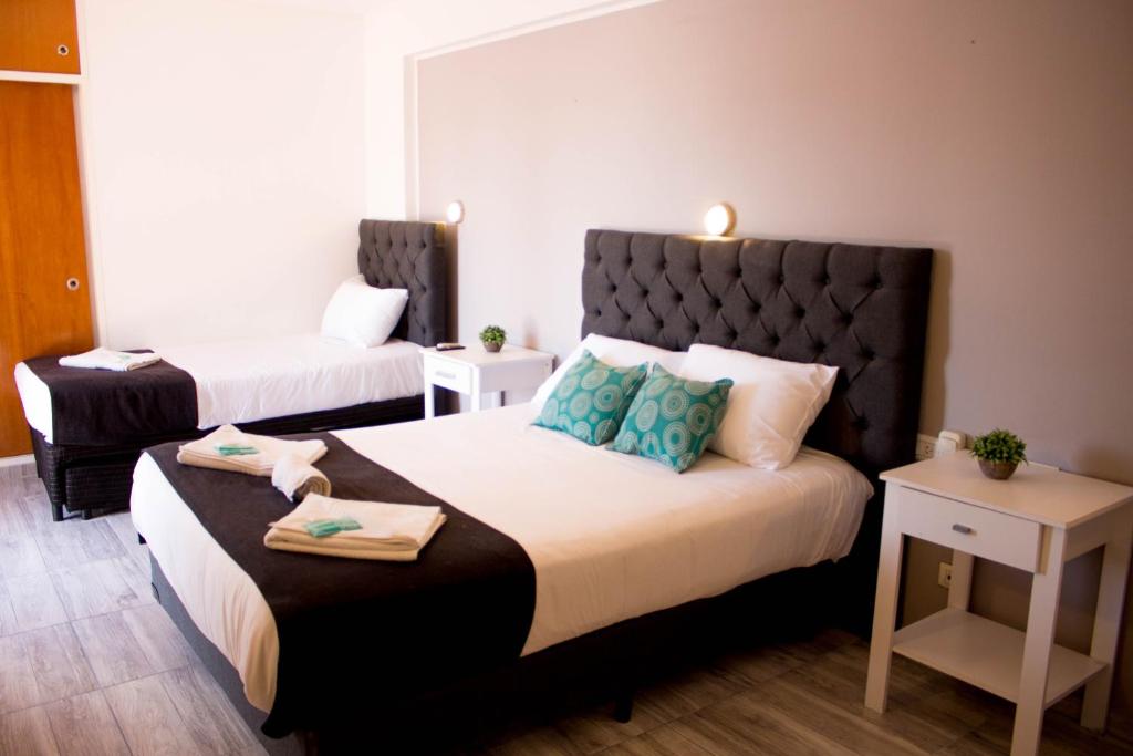 a hotel room with two beds and two tables at Hotel Terrazas by CPH in Villa Carlos Paz