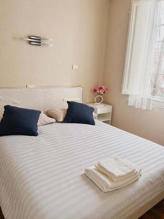 a large white bed with blue pillows and a window at Martina Fillungo Loft in Lucca