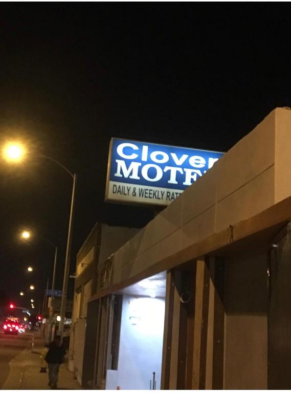 a sign on the top of a store at night at Clover motel in Lynwood
