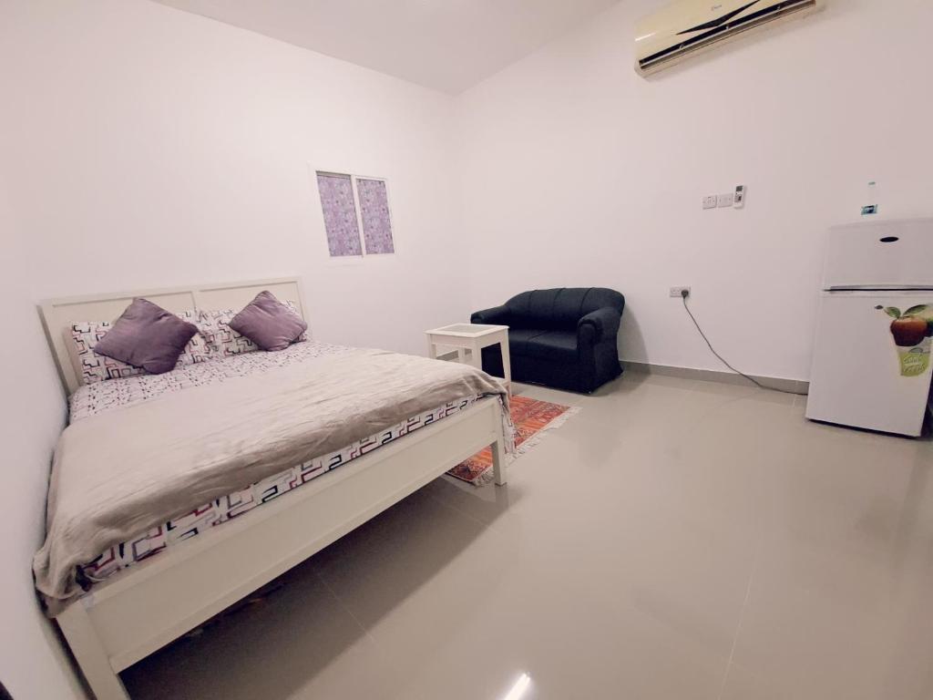 a white room with a bed and a chair at Easy Stay in Al Ain
