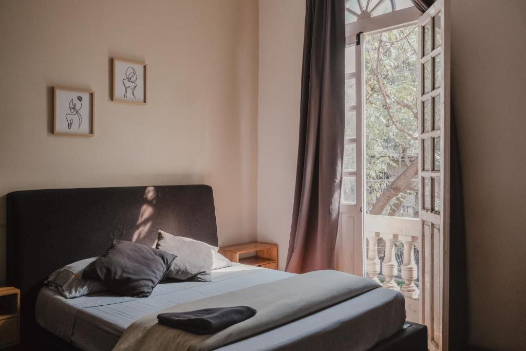 a bedroom with a bed and a window and a door at U-CO Live Roma Norte in Mexico City
