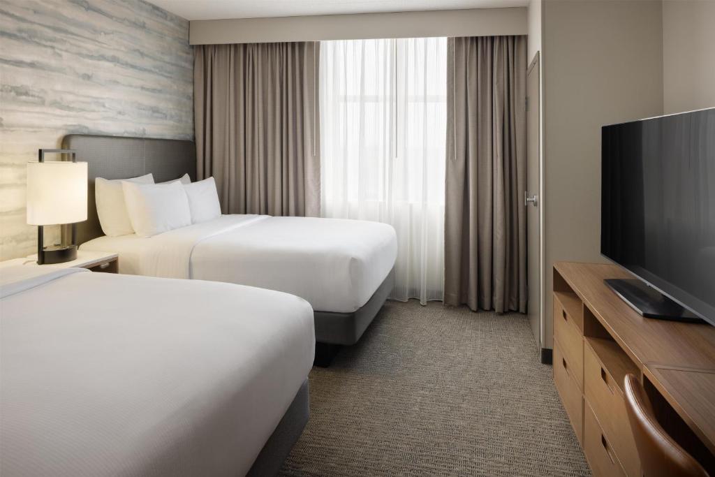 a hotel room with two beds and a flat screen tv at Embassy Suites Lexington in Lexington