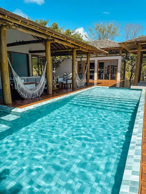 a swimming pool with hammocks and a house at Orixás Residence -Casa Yemanja Morro in Cairu