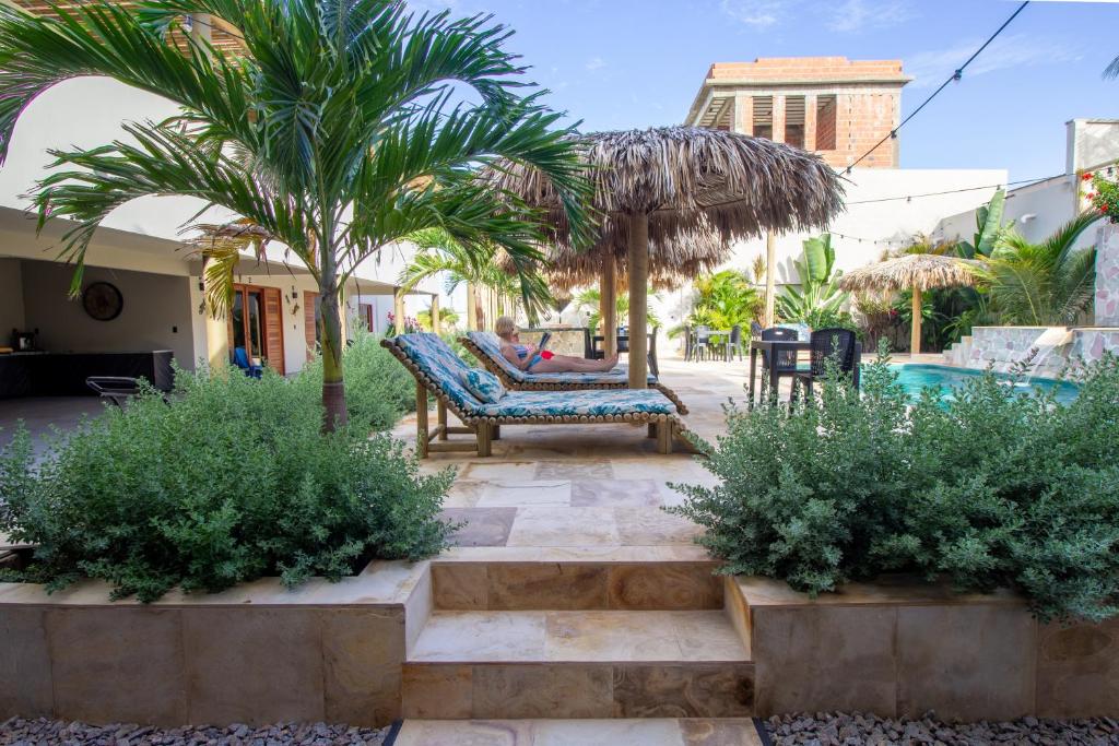 a patio with a bench and palm trees and a pool at Casa Ananda Hotel Boutique in Canoa Quebrada