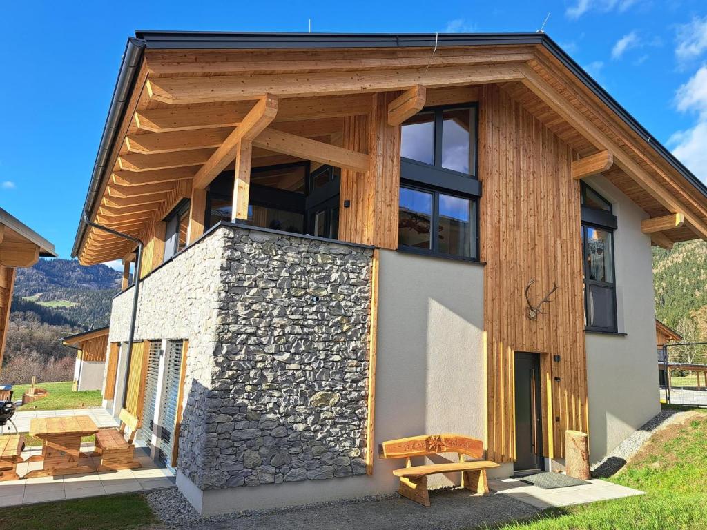 a house with a stone wall and wooden roof at Grebenzen Lodge Edelweiss in Sankt Lambrecht