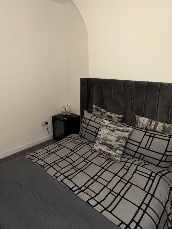a bedroom with a bed with a wooden headboard and pillows at City Apartment in Litherland