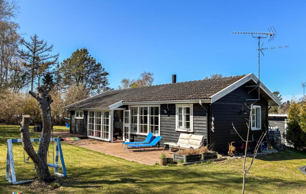 a black house with a porch and a blue chair at Amazing Home In Græsted With Wifi in Græsted