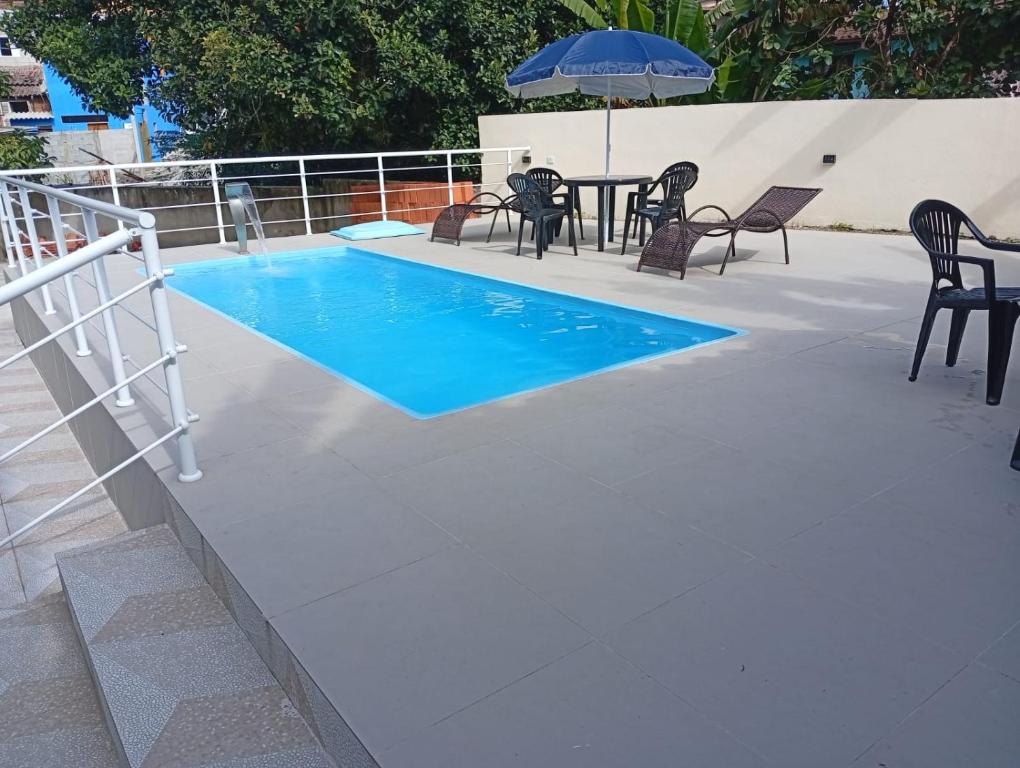 a pool with a table and chairs and an umbrella at Acomodações Souza in Ilhabela