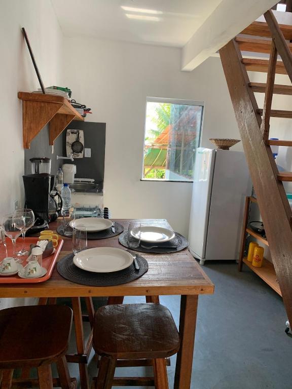 a kitchen with a wooden table with plates on it at Apartamento com Terraço na Gamboa do Morro in Cairu