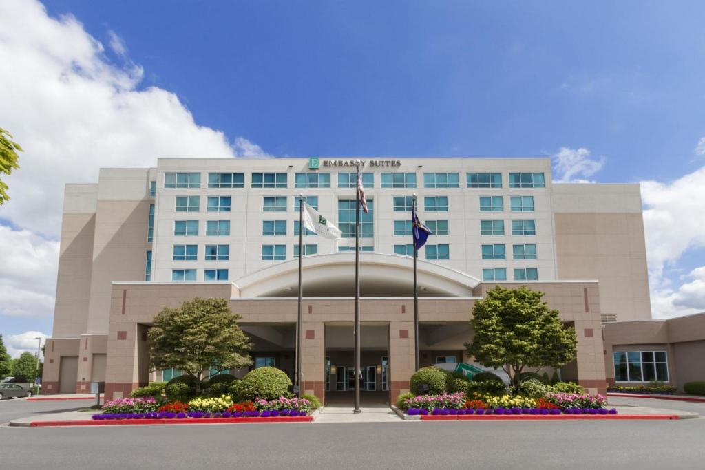 a large building with flowers in front of it at Embassy Suites by Hilton Portland Airport in Portland