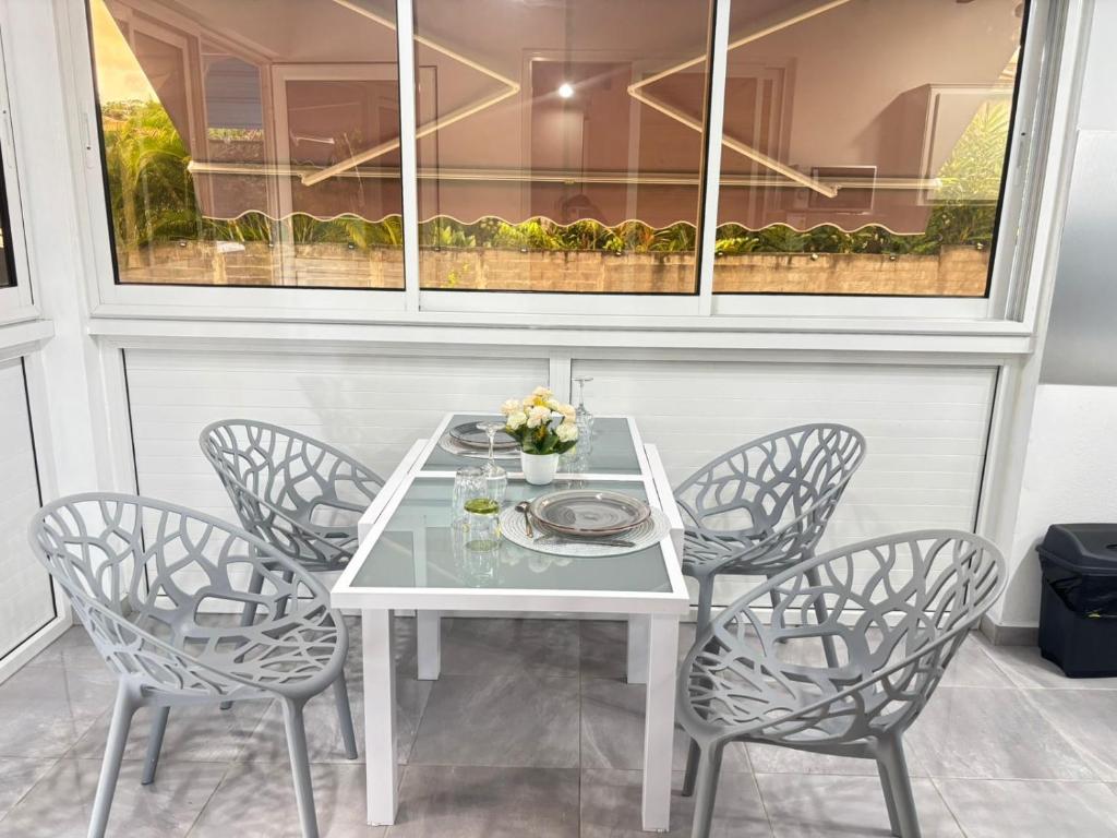 a white table with four chairs and a white table at L'Abri BEAUCI- TURLET in Goyave