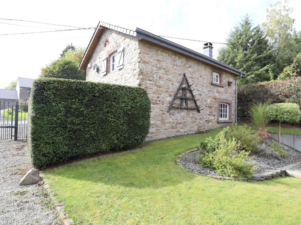 a stone house with a hedge in front of it at Le Fournil in Manhay