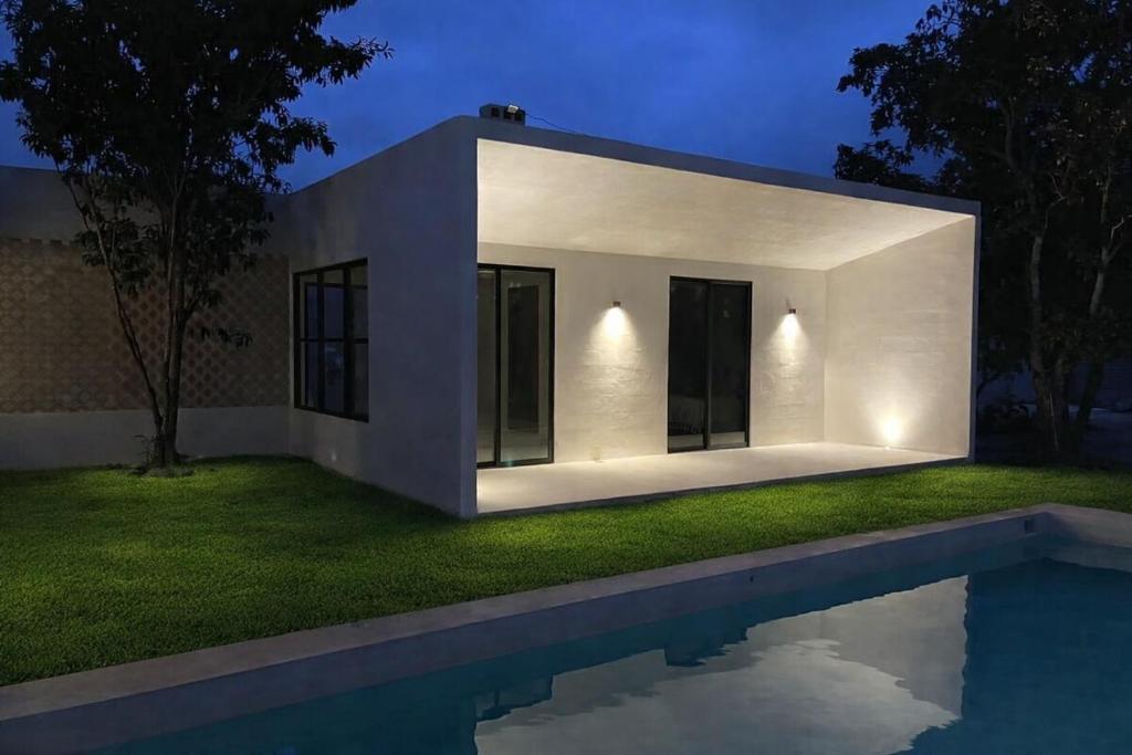 a white house with a swimming pool at night at Casa Nahox in Hunucmá