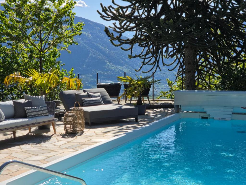 a pool with couches and chairs next to a mountain at Michael Am Waal in Schenna