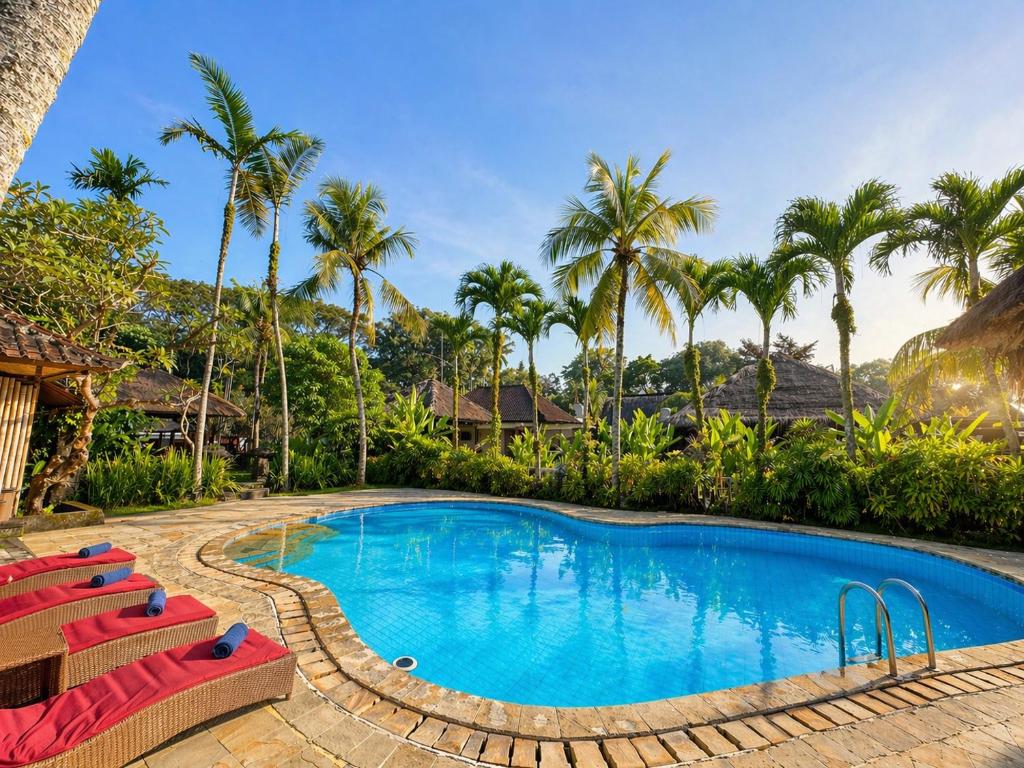 a swimming pool with red chairs and palm trees at Saren Indah Hotel in Ubud