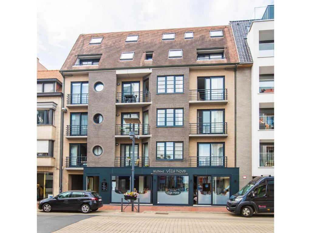a large brick building with cars parked in front of it at Villa Nova - 0402 + box 24 in Middelkerke