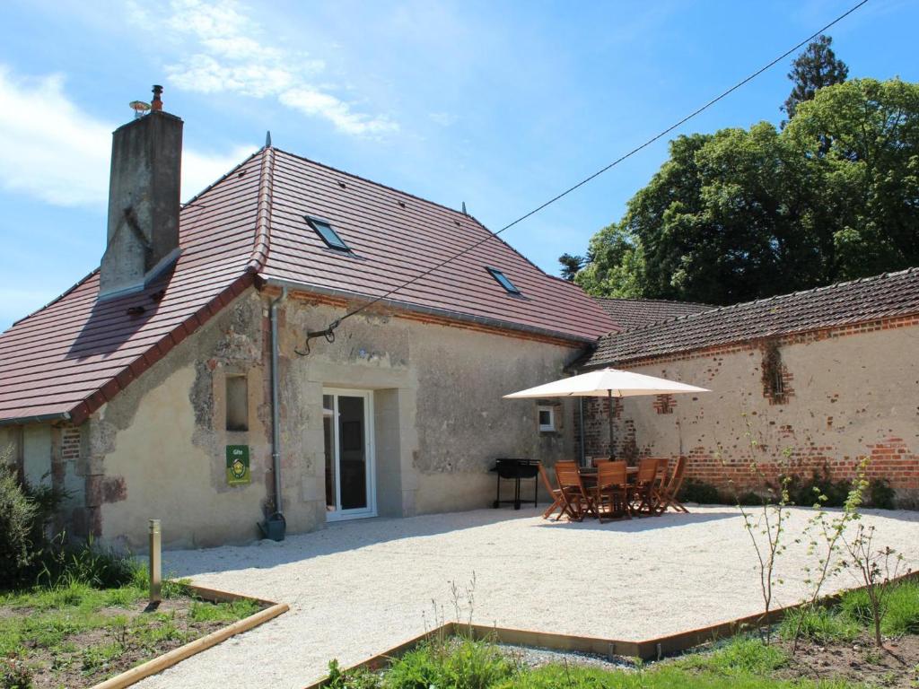 a building with a table and an umbrella at Gîte de charme à la campagne - 6 pers. - FR-1-489-17 in Bagneux