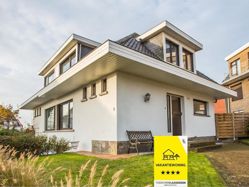 a house with a yellow sign in front of it at Villa Tamarisk - + box in Middelkerke
