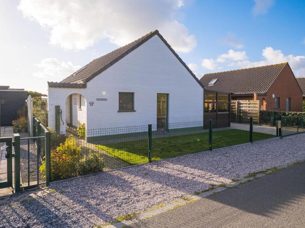 a white house with a fence in front of it at Westenwind - Nr. 3 + park. in Middelkerke