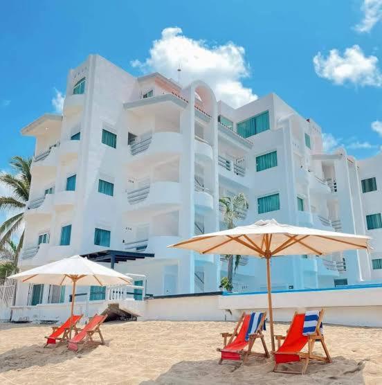 a group of chairs and umbrellas on a beach at Best Western Plus Luna del Mar in Manzanillo