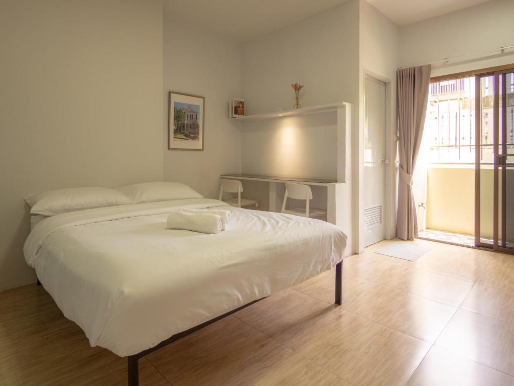 a white bedroom with a bed and a window at Prukpibul Apartment in Bangkok