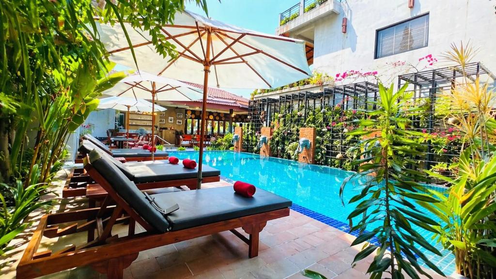 a resort with a swimming pool with chairs and an umbrella at Grange Boutique Siem Reap in Siem Reap