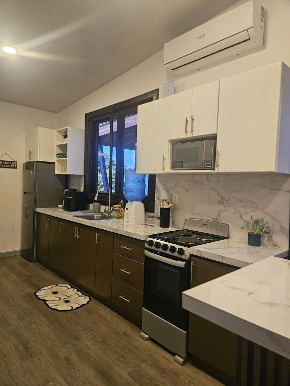 a kitchen with white cabinets and a stove top oven at Sea view house in Utila
